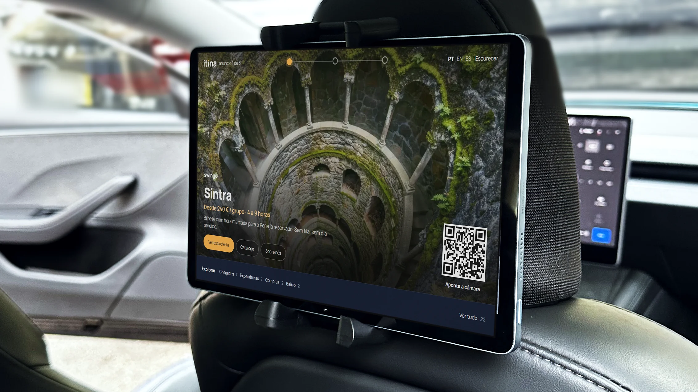O tablet no encosto de um Tesla da frota, com um anúncio de passeios a Sintra e a barra Explorar